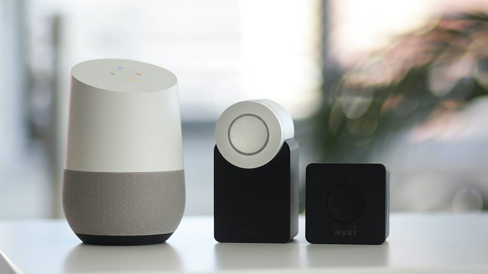 white and gray Google smart speaker and two black speakers