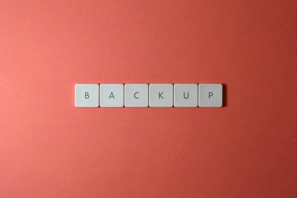 Free Close-up of keyboard keys spelling 'BACKUP' placed on a coral-colored surface. Stock Photo